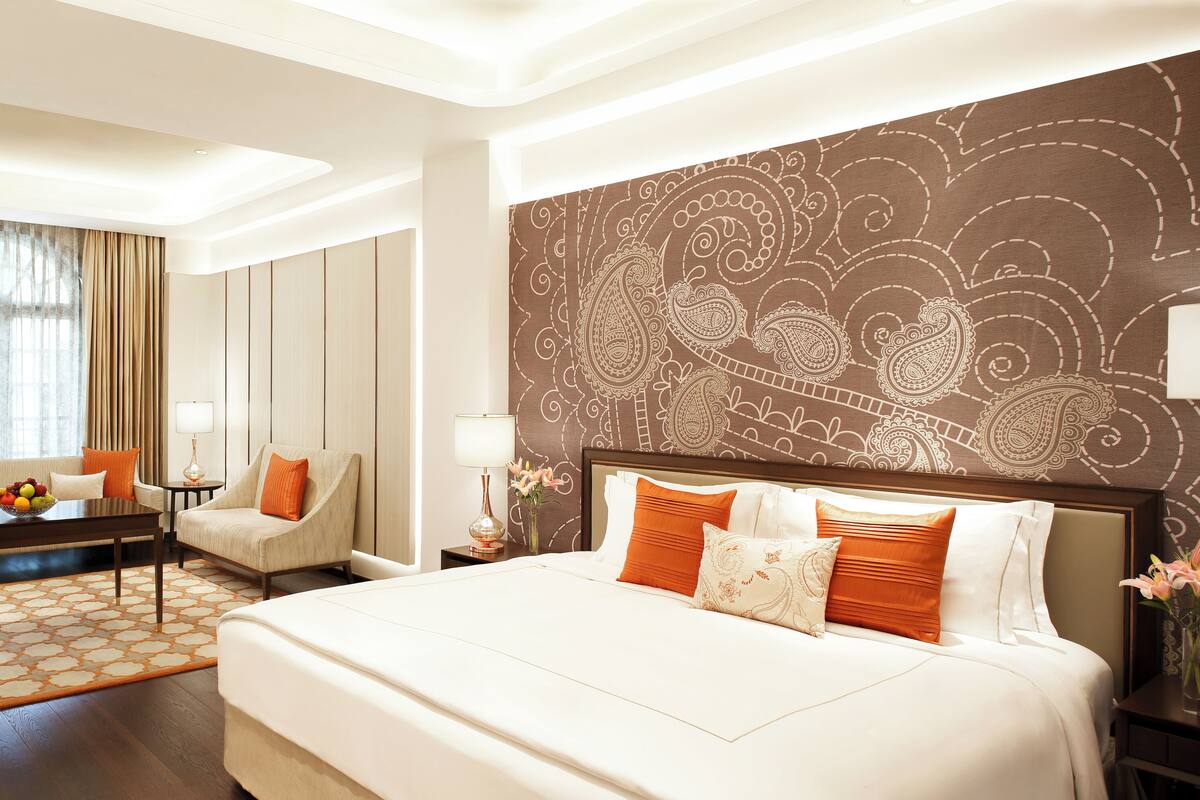 A hotel room with a large bed, a sofa, a desk, and a dining table.