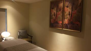 Una habitación de hotel con una cama grande, una silla y un cuadro colgado en la pared.