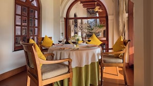 A dining area with a round table, wooden chairs, and a green tablecloth. - Taj Kumarakom Resort & Spa, Kerala (Kottayam)