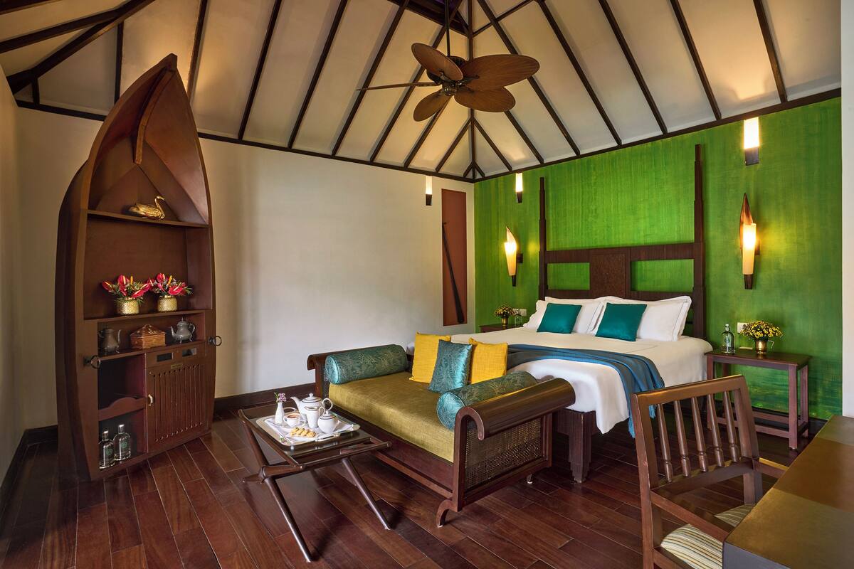 A hotel room with a bed, a sofa, a wooden cabinet, and a ceiling fan.