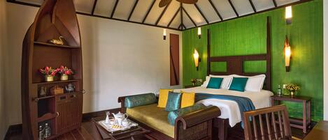 A hotel room with a bed, a sofa, a wooden cabinet, and a ceiling fan.