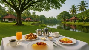 A breakfast table with croissants, eggs, and juice, set against a backdrop of a lake and palm trees. - Taj Kumarakom Resort & Spa, Kerala (Kottayam)