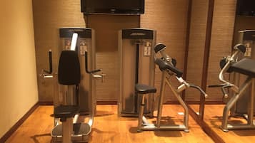 Ett gym med konditionsmaskiner och en tv som är monterad på väggen.