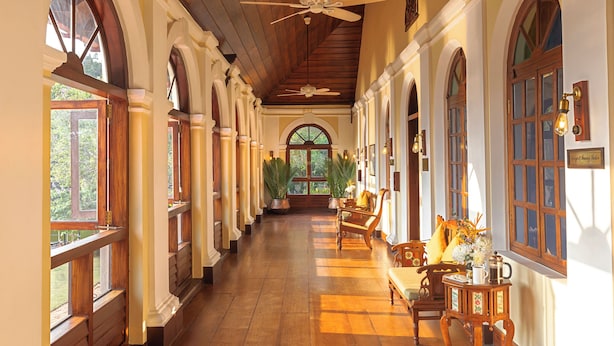 A hallway with wooden floors, arched windows, and ceiling fans. - Taj Kumarakom Resort & Spa, Kerala (Kottayam)