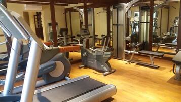 Een sportschool met cardioapparatuur, krachttraining apparaten en spiegels.