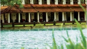 A colonial-style building with a tiled roof and multiple arches, situated by a body of water. - Taj Kumarakom Resort & Spa, Kerala (Kottayam)