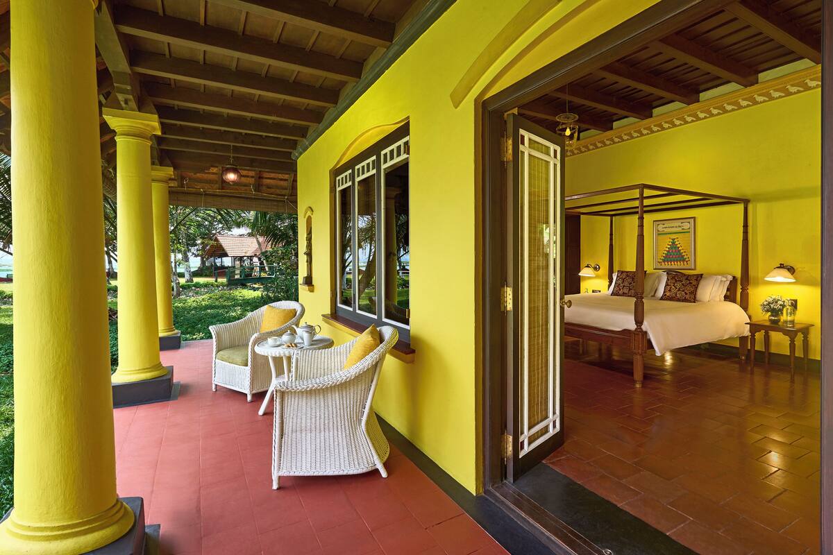 A yellow room with a bed, a window, and a chair.
