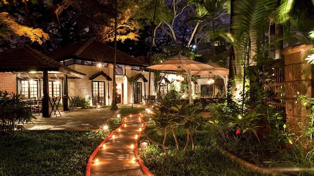 Un sendero iluminado por luces y velas, que conduce a un edificio con varias habitaciones.