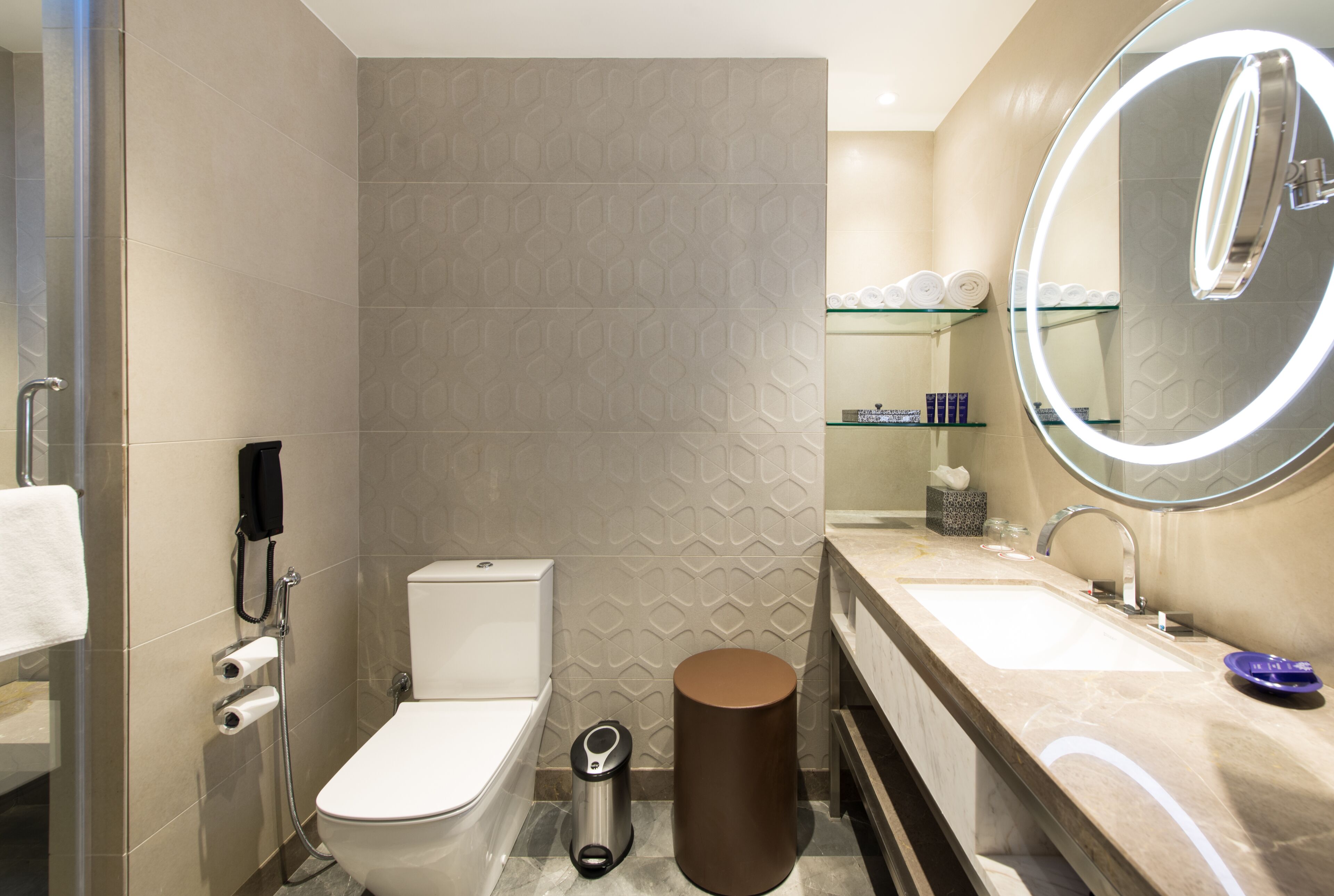 A modern bathroom with a toilet, bidet, and a large mirror with a light.