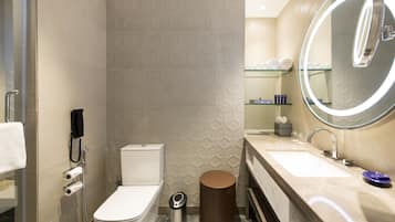 A modern bathroom with a toilet, bidet, and a large mirror with a light.