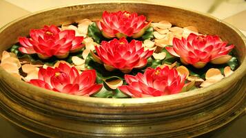 Un cuenco decorativo con flores rojas y hojas verdes.