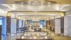 Un restaurante moderno con zona de comedor central, una barra y una cocina al fondo.