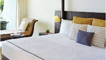 Een hotelkamer met een groot bed, een stoel, een nachtkastje en een lamp.