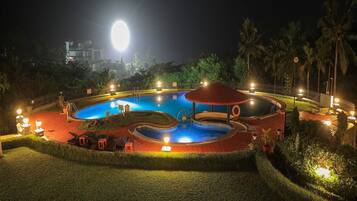 Relax by the pool surrounded by lush greenery and comfortable lounge chairs.