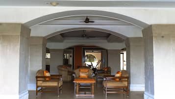 A lobby with a seating area featuring sofas and armchairs, a ceiling fan, and a view into the adjacent room.