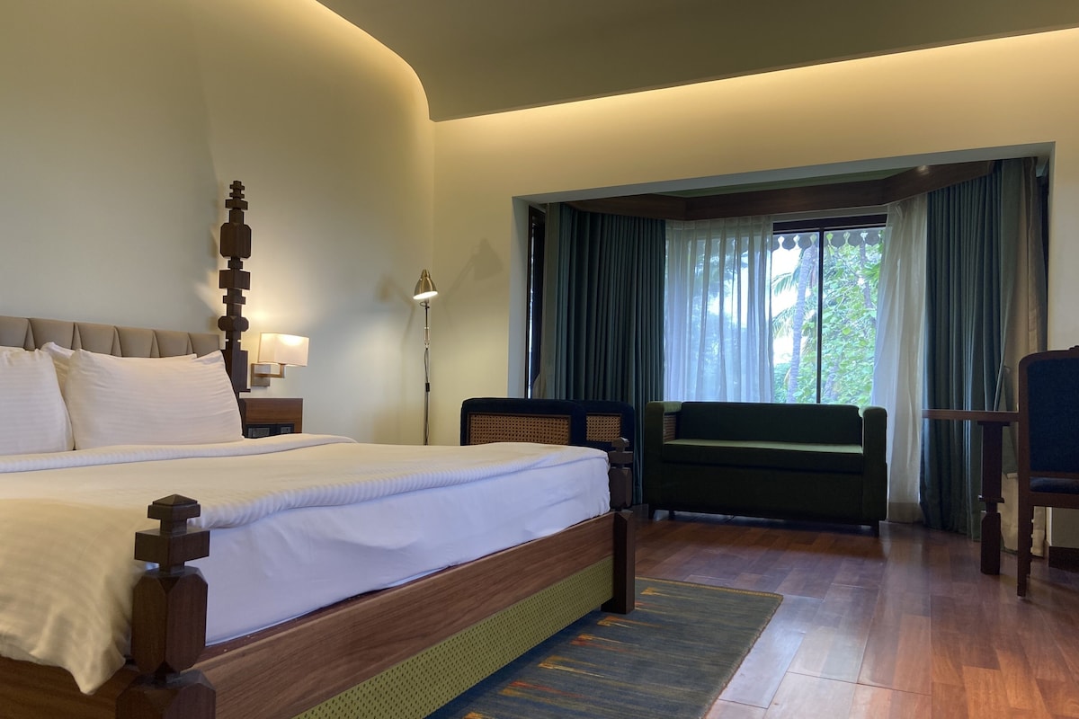 Une chambre d’hôtel avec un grand lit, un bureau, une chaise et une fenêtre avec des rideaux.
