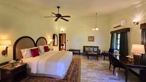 A hotel room with a large bed, a desk, a chair, a ceiling fan, and a window with curtains. - Gateway Madurai (Madurai)