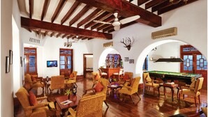 A spacious lounge with wooden flooring, multiple seating areas, a pool table, and a bar.