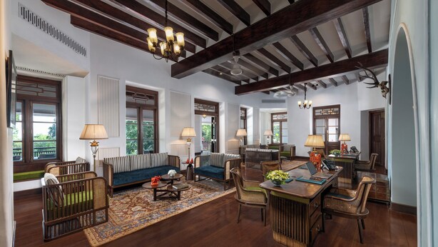 A spacious living area with a high ceiling, wooden beams, and a dining area with wicker furniture.