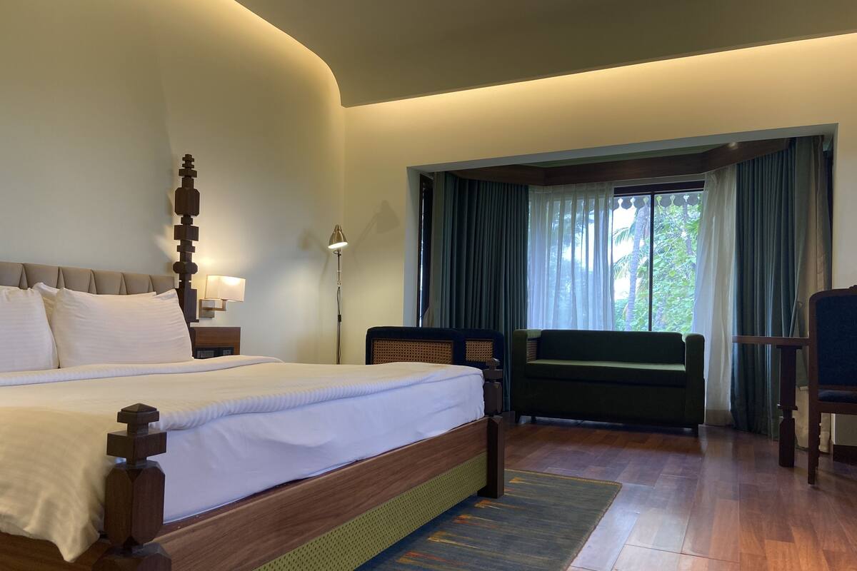 Une chambre d’hôtel avec un grand lit, un bureau, une chaise et une vue sur la verdure.