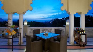 An outdoor dining area with a table set for two, surrounded by wicker chairs, under a decorative archway. - Gateway Nashik (Nashik)