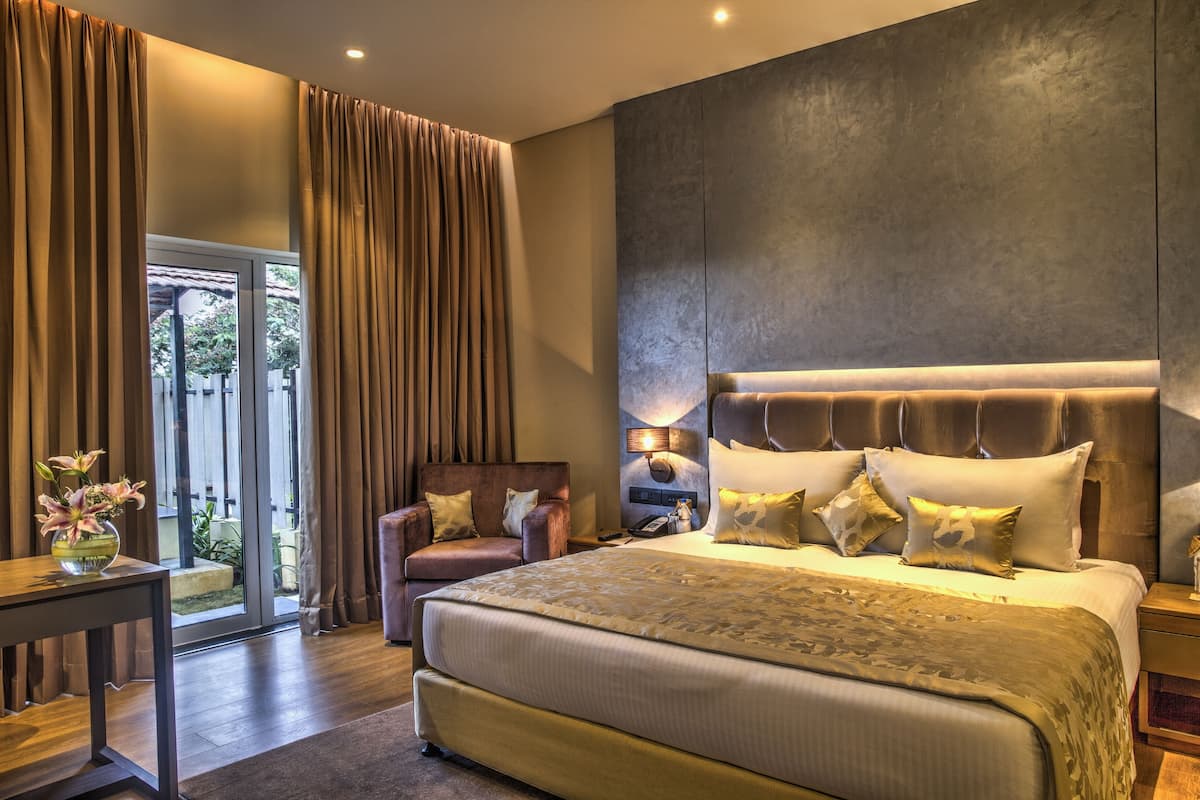 A spacious bedroom with a large bed, a chair, a nightstand, and a view of the outdoors through a sliding door.