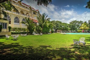 Un hotel con piscina, mobiliario exterior y abundante vegetación.