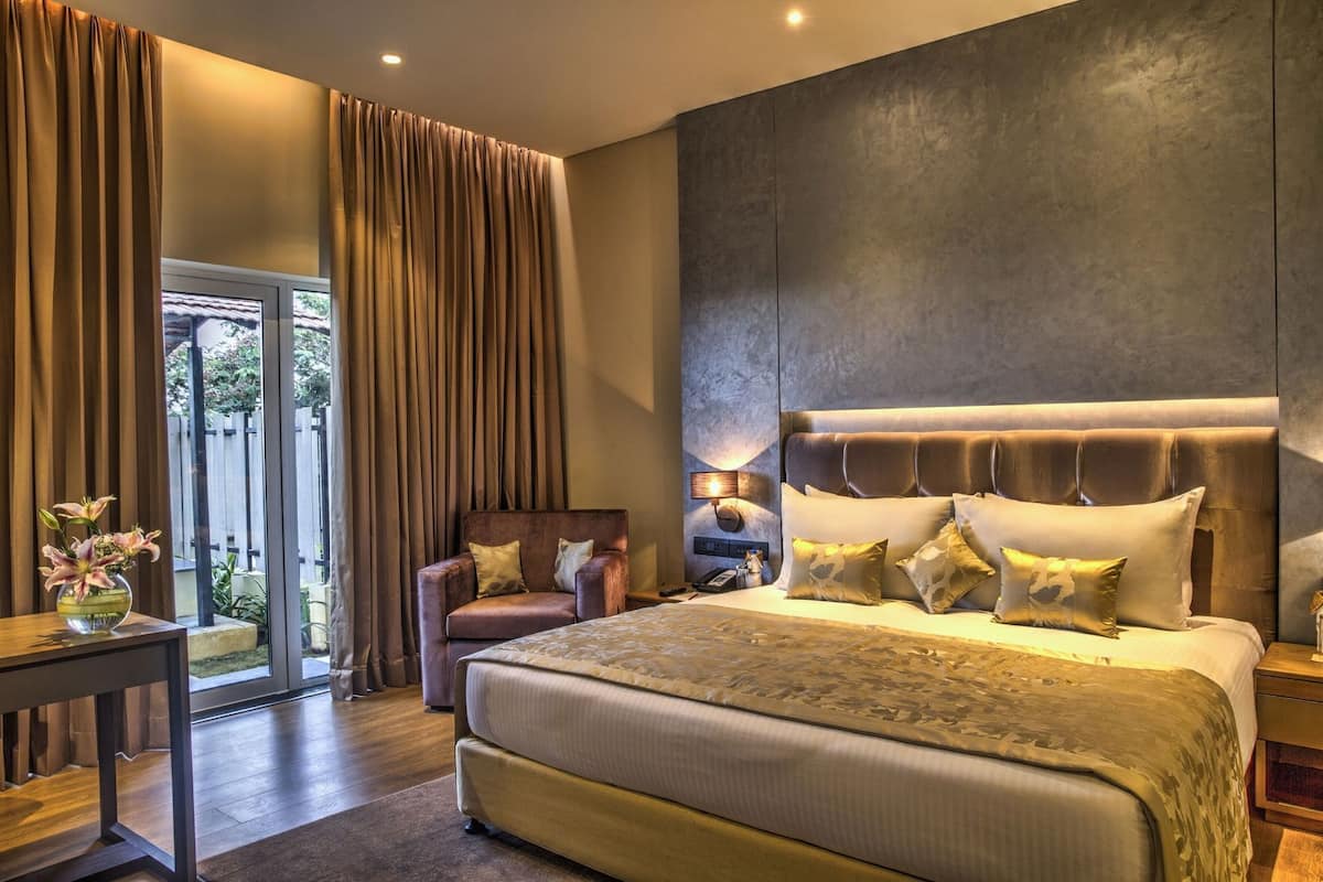 A bedroom with a large bed, a chair, a bedside table, and a view of the outdoors.