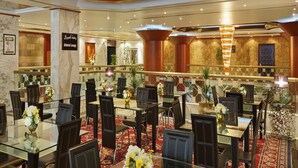Un comedor amplio con varias mesas y sillas, un candelabro y un cartel que indica el lugar como 'Admiral Lounge'.