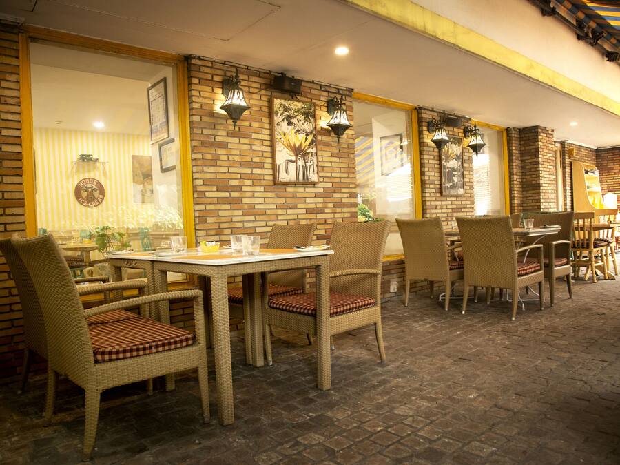 An outdoor dining area with wicker furniture and brick walls.