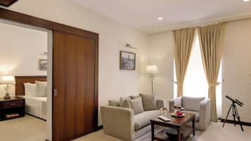 A hotel room with a bed, a sofa, a coffee table, a lamp, a picture on the wall, and a telescope.
