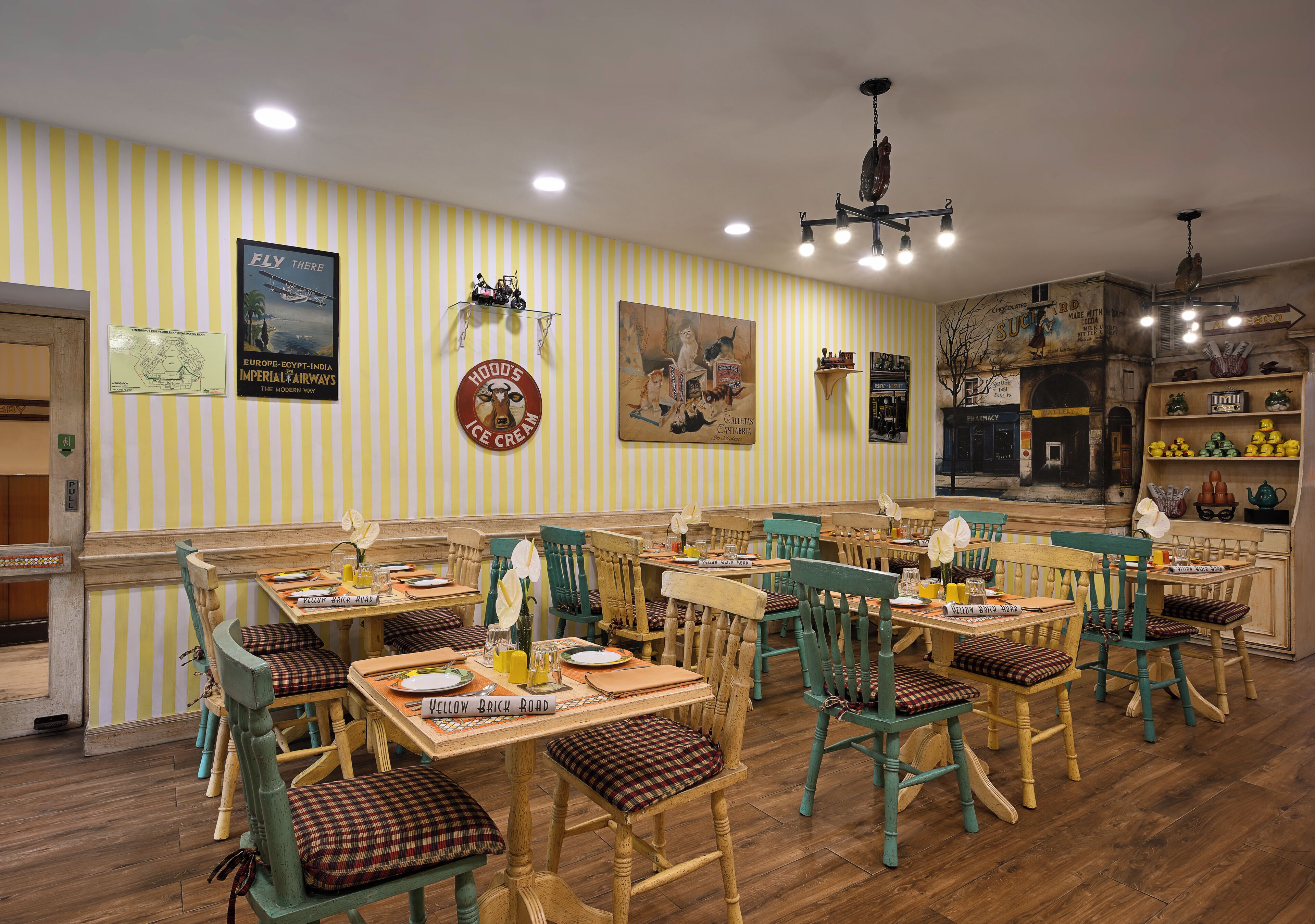 A restaurant with striped wallpaper, vintage posters, and wooden furniture.
