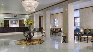 A spacious lobby with a reception desk, seating area, and a large chandelier. - Ambassador, New Delhi - IHCL SeleQtions (New Delhi)