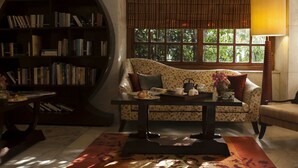 A cozy reading nook with a sofa, a bookshelf, and a table with a lamp. - Ambassador, New Delhi - IHCL SeleQtions (New Delhi)
