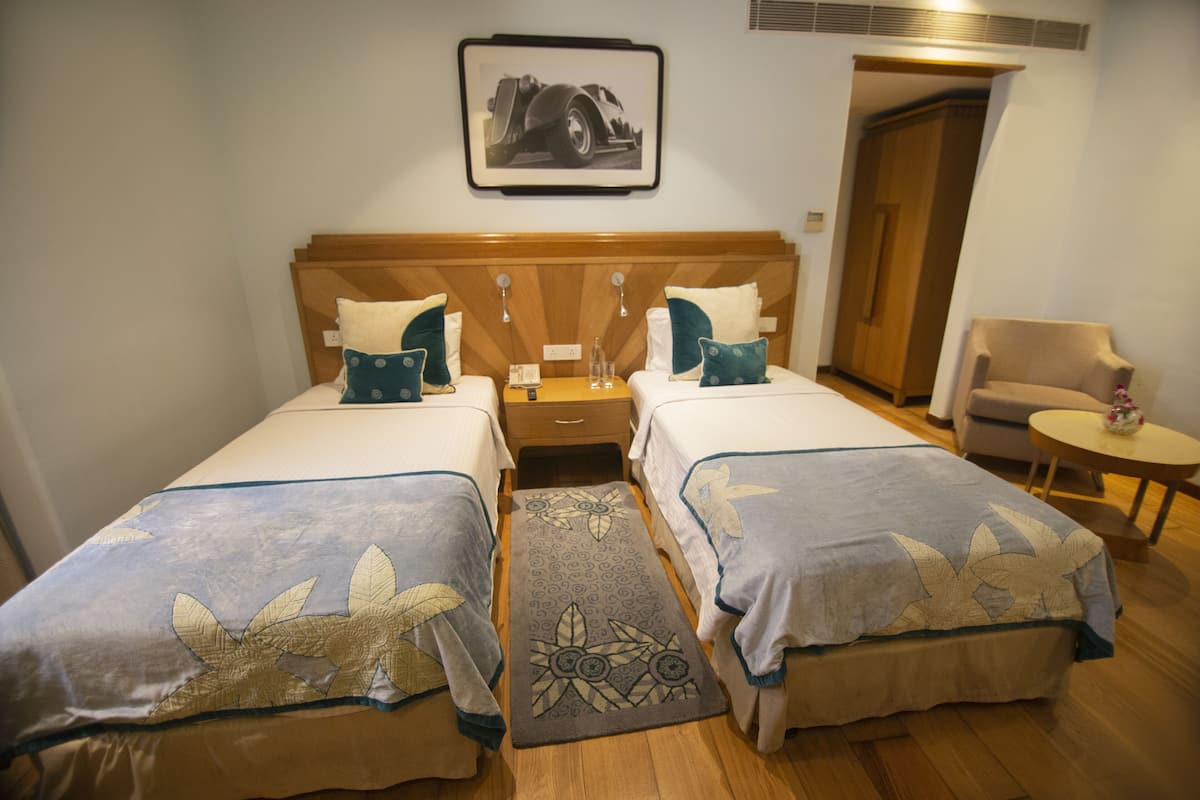 A hotel room with two beds, a wooden headboard, a small table, and a chair.