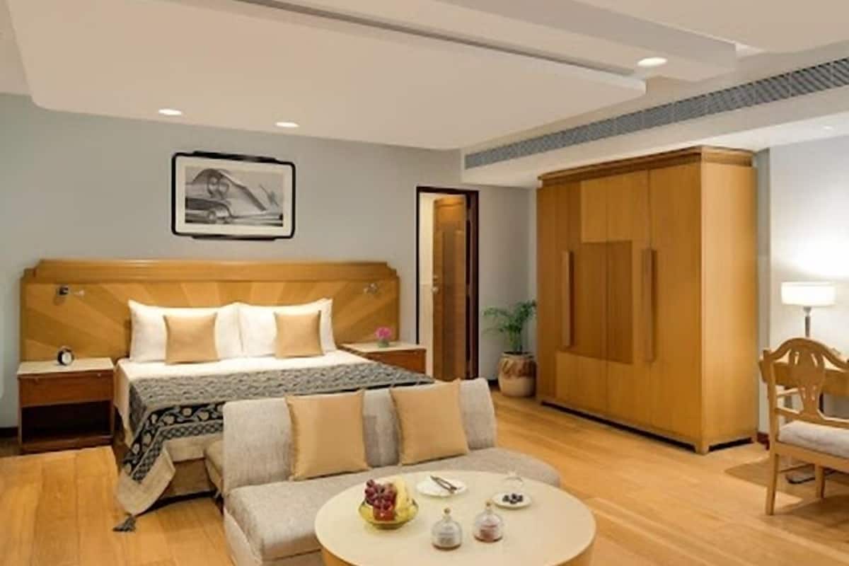 A hotel room with a bed, a sofa, a round table, a wardrobe, and a nightstand.