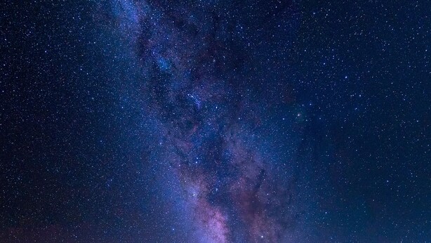 Zona pranzo all'aperto con mobili in vimini e tavoli, sotto un cielo stellato.