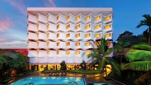 Un hotel de varios pisos con un área de piscina en primer plano.
