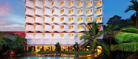 A multi-story hotel with a pool area in the foreground.