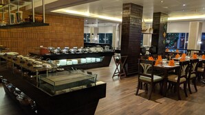 Montaje de bufé con varias estaciones de servicio, una vitrina central y un área de comedor con mesas y sillas.