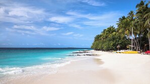 A beach with clear turquoise waters, white sand, and palm trees. - Taj Coral Reef Resort & Spa Maldives – A Premium All Inclusive Resort (Hembadhu Island)