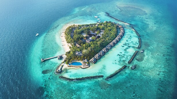 An aerial view of a tropical island resort with overwater bungalows, a swimming pool, and clear turquoise waters. - Taj Coral Reef Resort & Spa Maldives – A Premium All Inclusive Resort (Hembadhu Island)