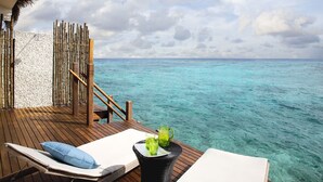 A wooden deck with lounge chairs and a table, overlooking turquoise waters. - Taj Coral Reef Resort & Spa Maldives – A Premium All Inclusive Resort (Hembadhu Island)