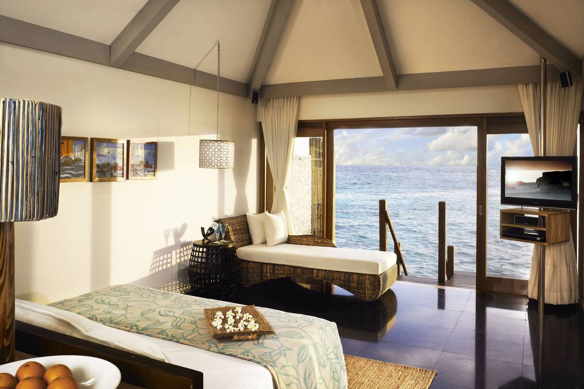 A bedroom with a bed, a TV, a view of the sea, and a balcony.