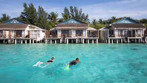 A resort with overwater bungalows connected by walkways over clear turquoise water. - Taj Coral Reef Resort & Spa Maldives – A Premium All Inclusive Resort (Hembadhu Island)