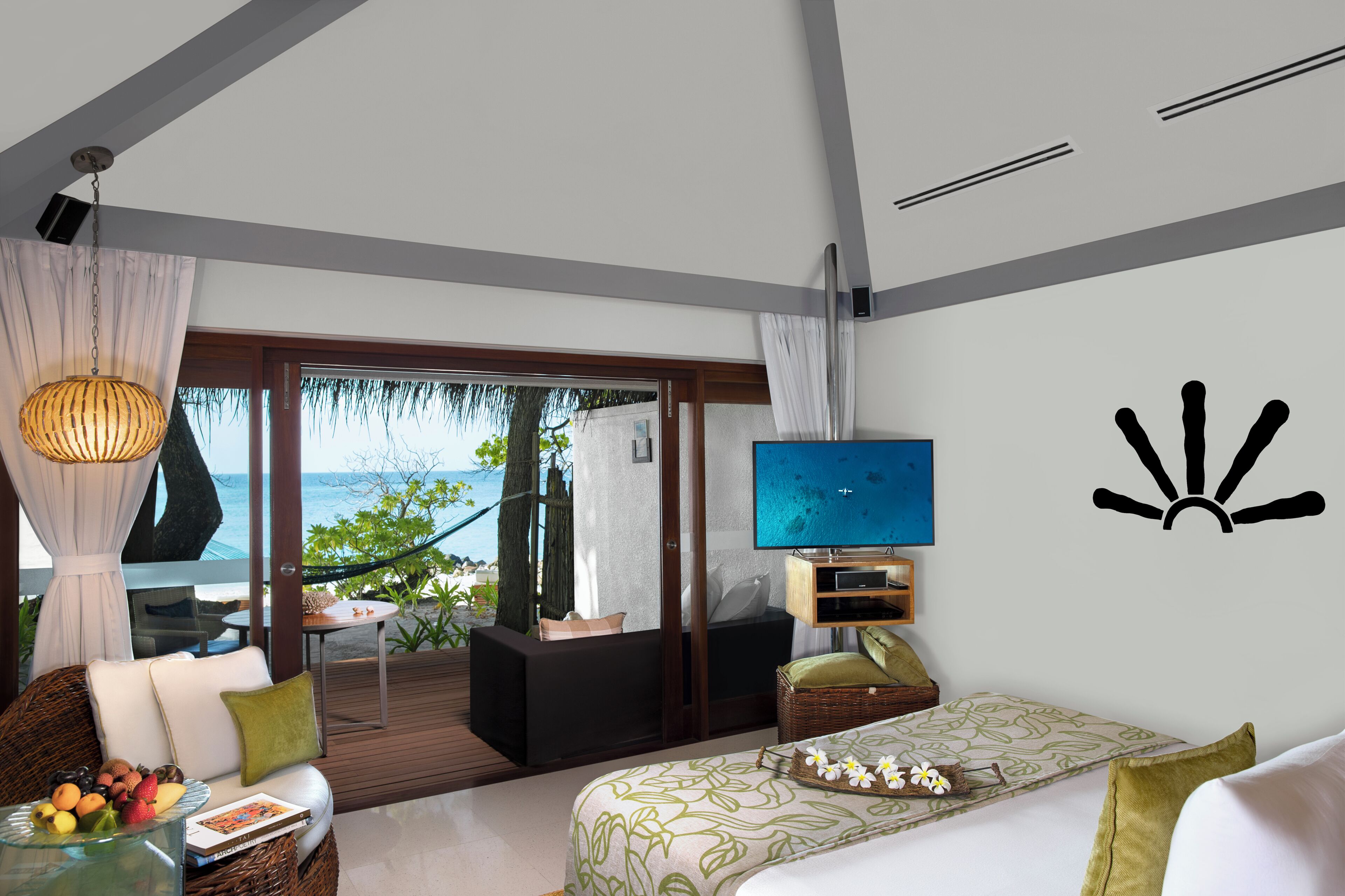 A modern hotel room with a balcony, a TV, and a bed with a view of the sea.