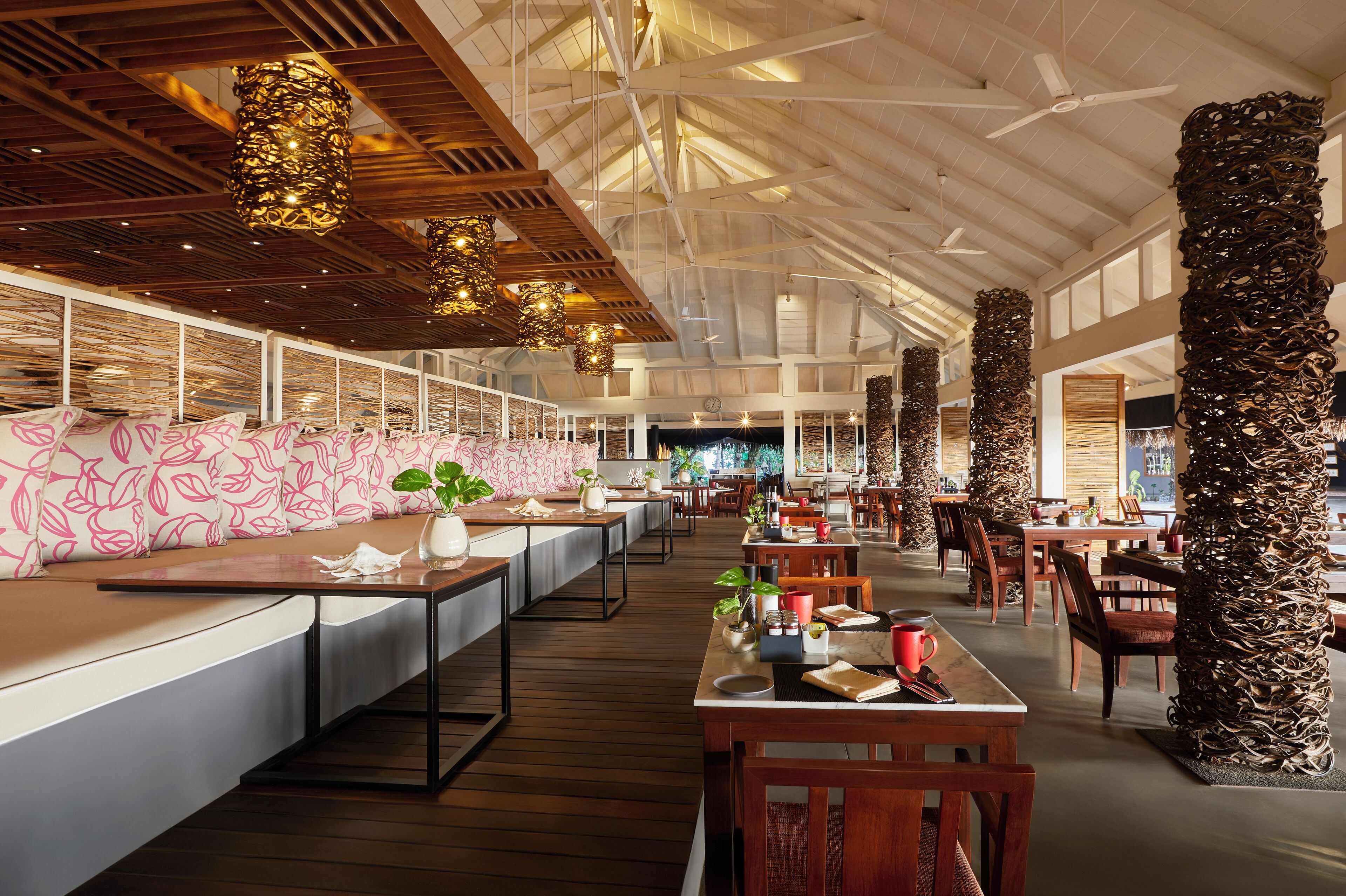 A spacious restaurant with high ceilings, wooden beams, and modern furnishings.