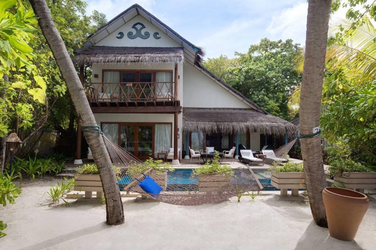 A two-story building with a thatched roof, a pool, and outdoor seating.