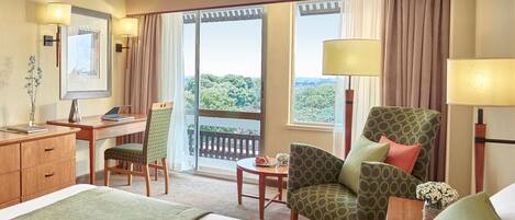 Una habitación de hotel con cama, escritorio, silla, mesa y vistas al exterior.