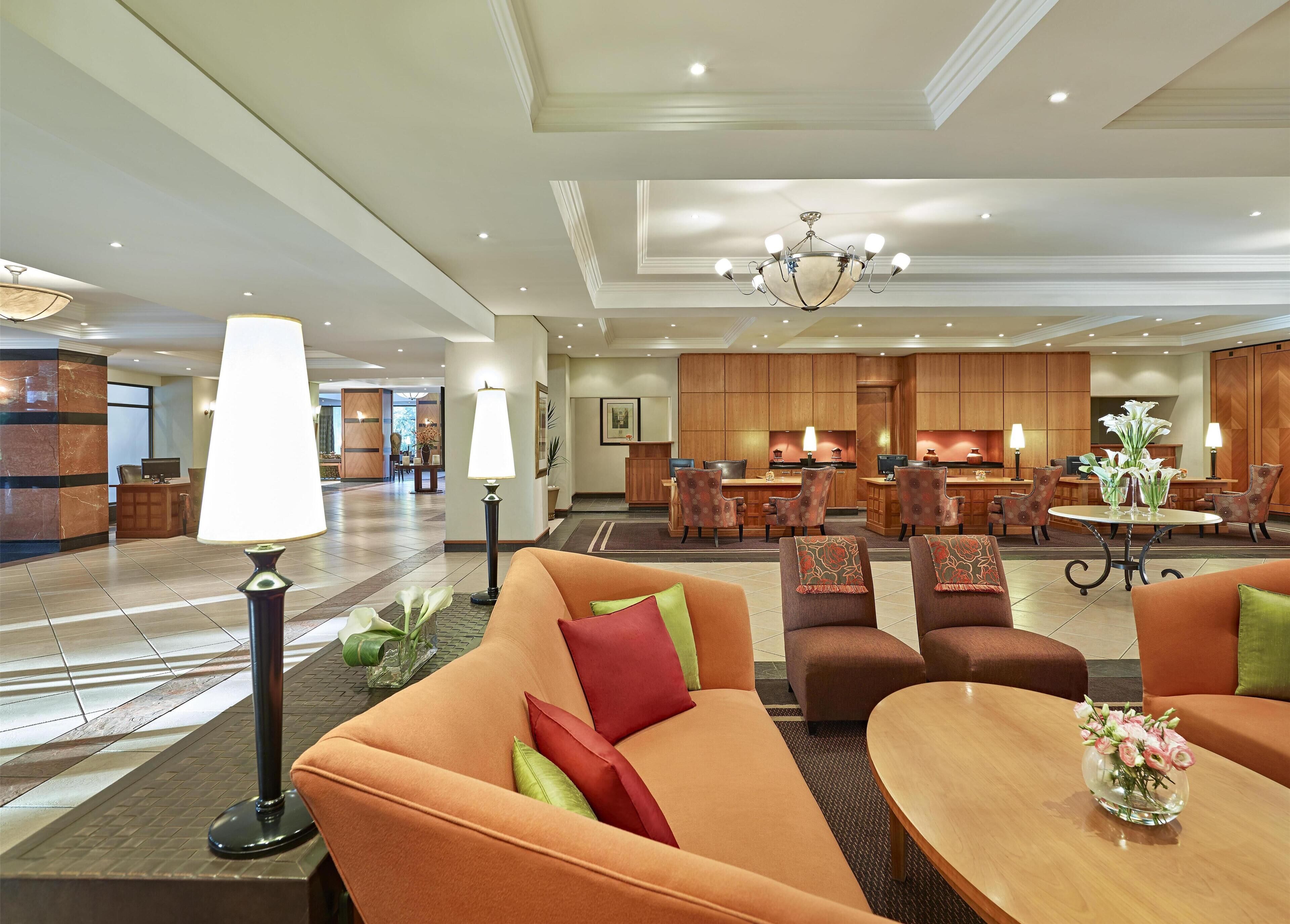 Un hall de hotel con recepción, zona de estar y área de comedor.